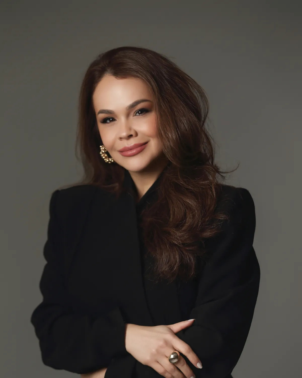 Dra. Vanessa Soares, dermatologista em Curitiba, de blazer preto, sorrindo com os braços cruzados.